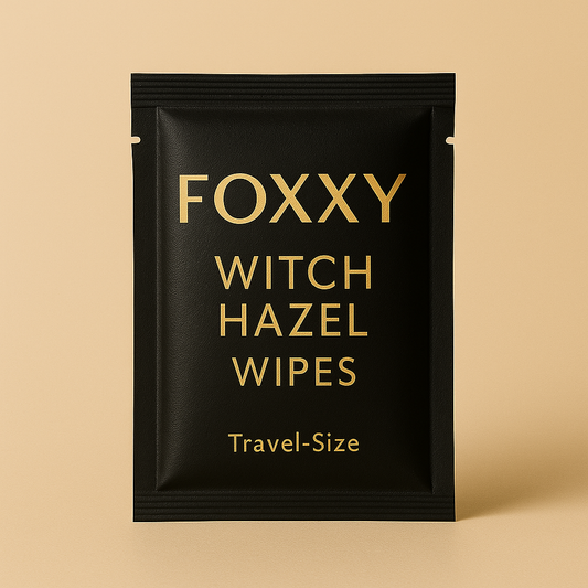Black travel-size packet of FOXXY Witch Hazel Wipes with gold lettering on a beige background.